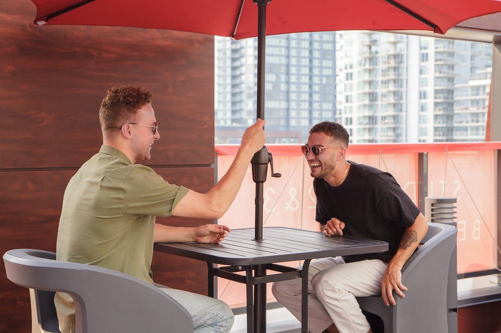 Residents under an umbrella on the rooftop patio